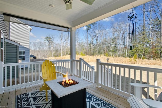 wooden deck with ceiling fan and a fire pit