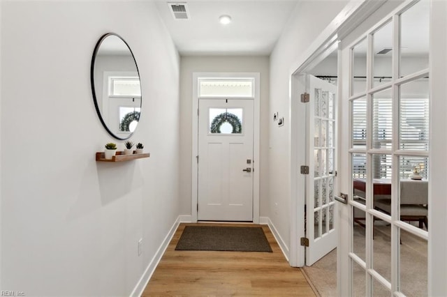 doorway to outside with light wood-style floors, baseboards, visible vents, and french doors