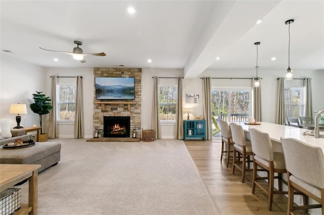 living room with a ceiling fan, recessed lighting, a stone fireplace, and baseboards