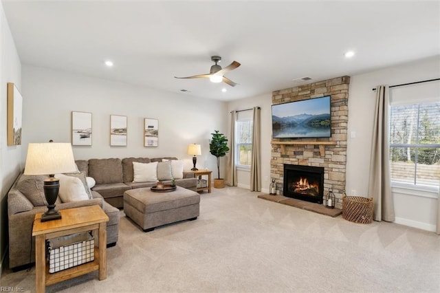 living room featuring baseboards, a stone fireplace, visible vents, and light colored carpet