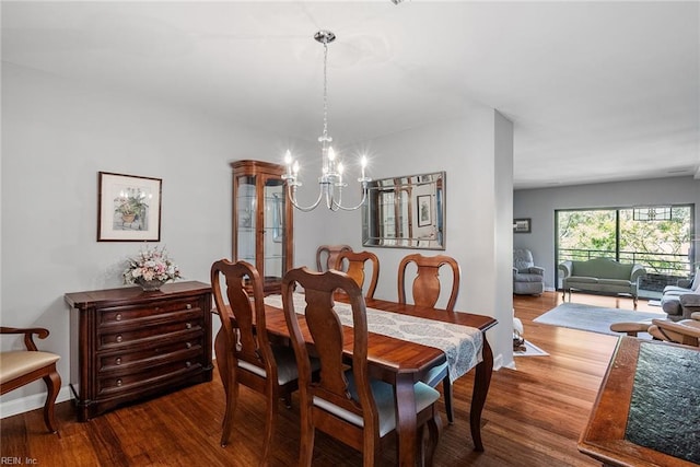 dining room with a notable chandelier, baseboards, and wood finished floors