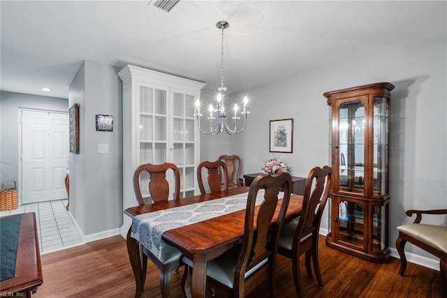 dining space featuring visible vents, a notable chandelier, baseboards, and wood finished floors