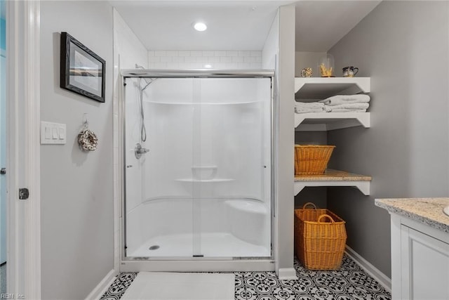 full bathroom with a stall shower, tile patterned flooring, vanity, and baseboards