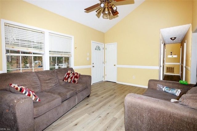 living room with ceiling fan, high vaulted ceiling, wood finished floors, visible vents, and baseboards