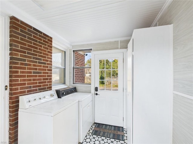 laundry area featuring laundry area, brick wall, tile patterned floors, and independent washer and dryer