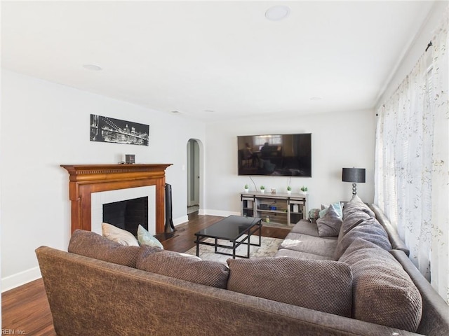 living room with dark wood-style floors, baseboards, and arched walkways