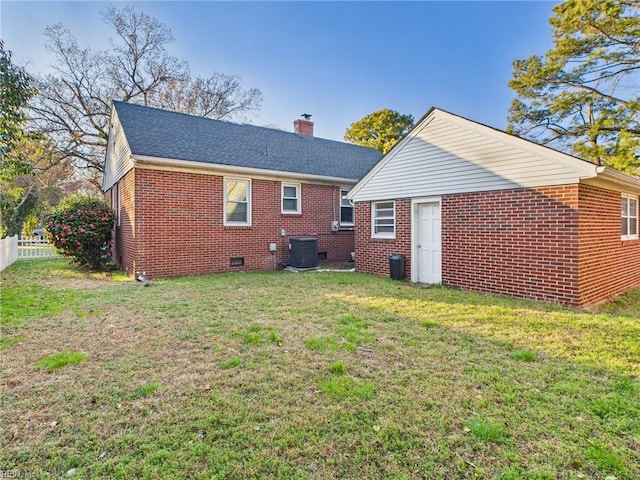 back of house with a chimney, crawl space, fence, a yard, and brick siding