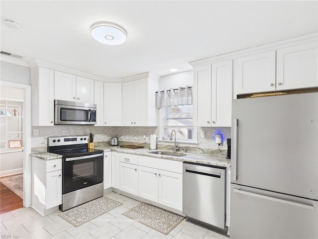 kitchen featuring appliances with stainless steel finishes, white cabinets, visible vents, and a sink