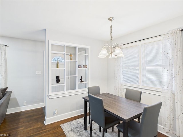 dining room featuring a notable chandelier, plenty of natural light, baseboards, and wood finished floors