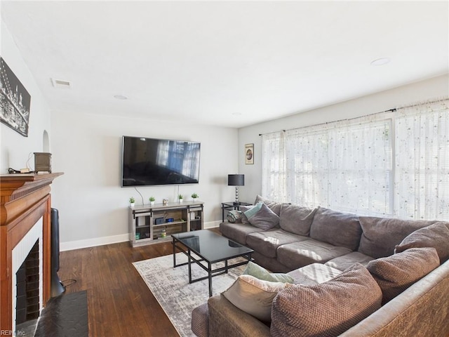 living room with a fireplace with flush hearth, baseboards, visible vents, and hardwood / wood-style floors