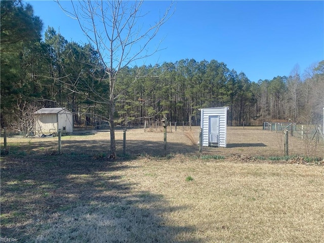 view of yard with an outdoor structure, fence, a view of trees, and a shed