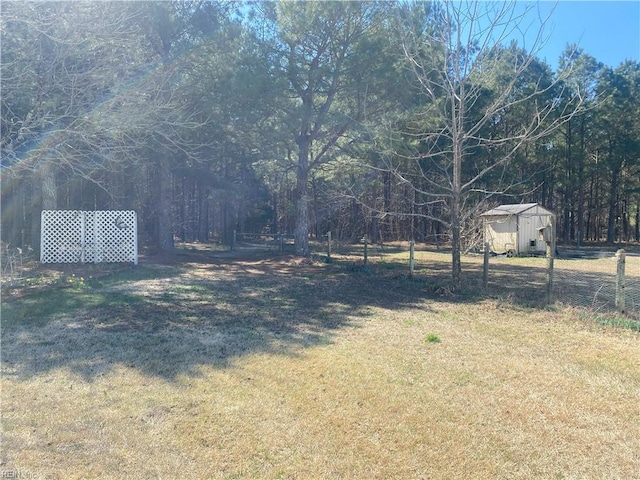 view of yard featuring an outbuilding, fence, and a shed