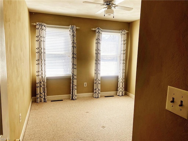 carpeted spare room with baseboards and a ceiling fan