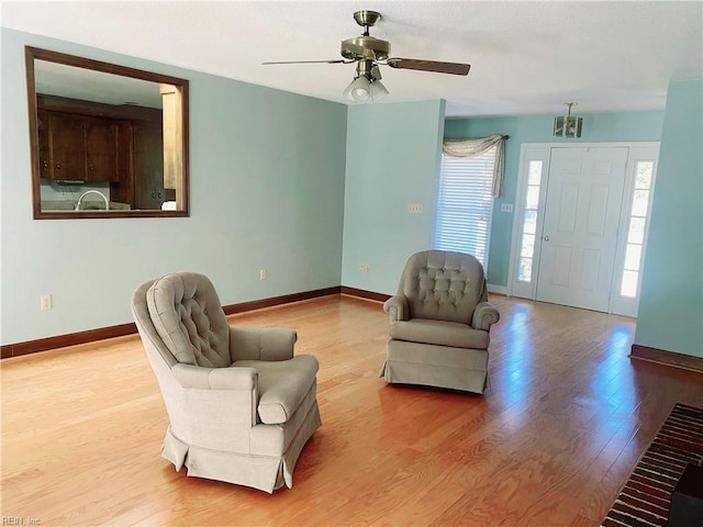 living room with a ceiling fan, baseboards, and wood finished floors