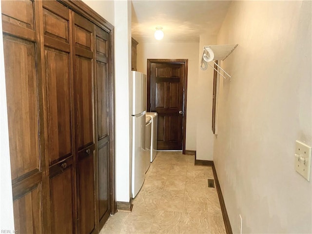 hall featuring washer and clothes dryer, visible vents, and baseboards