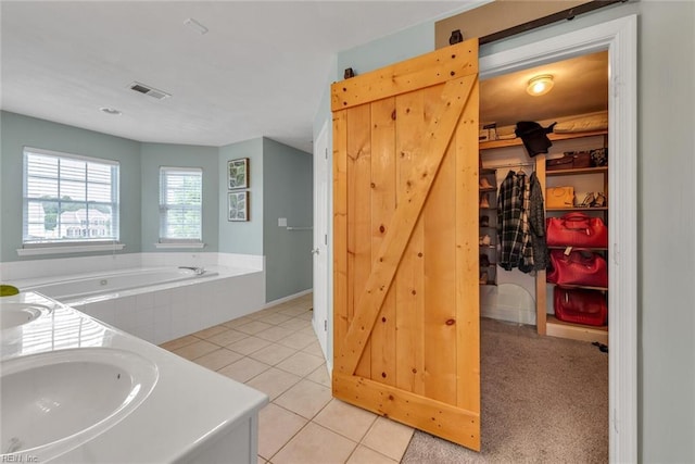 full bathroom featuring a sink, visible vents, a spacious closet, a bath, and tile patterned floors