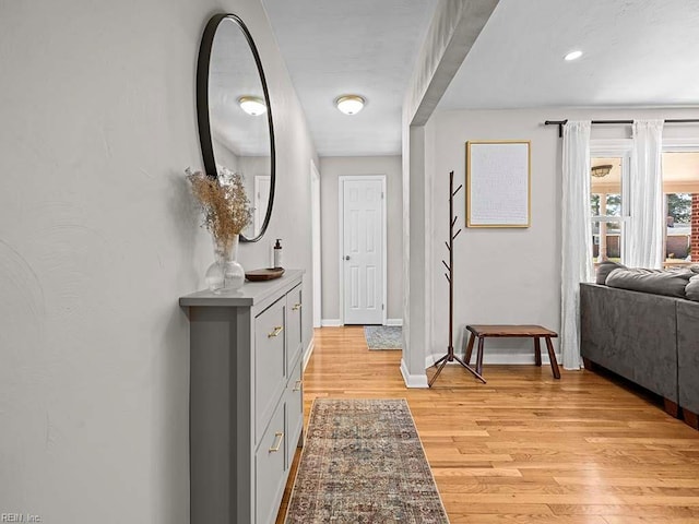 corridor featuring light wood finished floors and baseboards