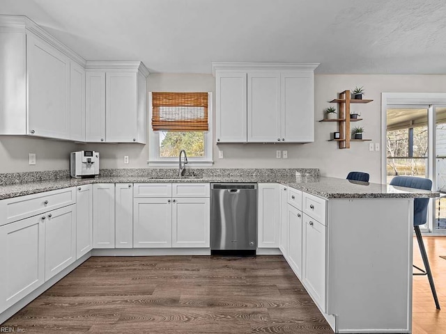 kitchen with a sink, a peninsula, white cabinetry, and dishwasher