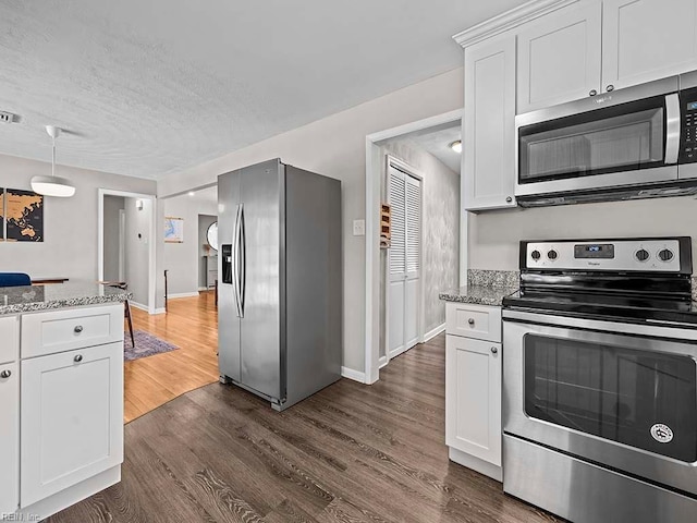 kitchen with dark wood-style floors, stainless steel appliances, light stone counters, and white cabinets