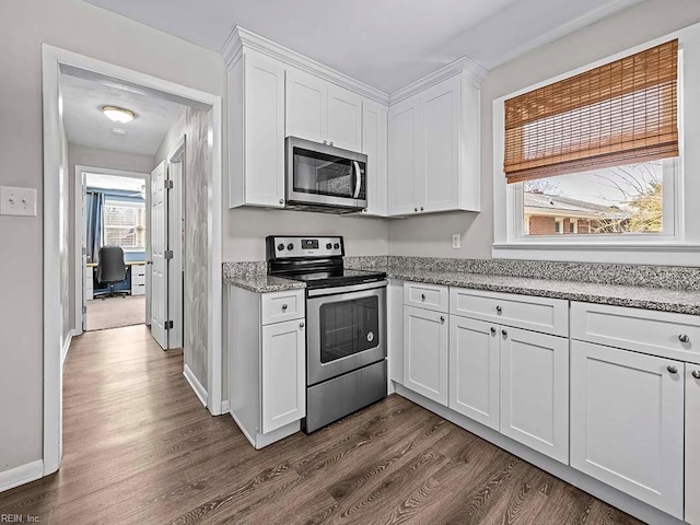 kitchen with light stone counters, stainless steel appliances, dark wood-type flooring, white cabinetry, and baseboards