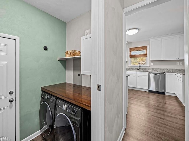 clothes washing area featuring laundry area, dark wood-style flooring, a sink, baseboards, and washer and dryer