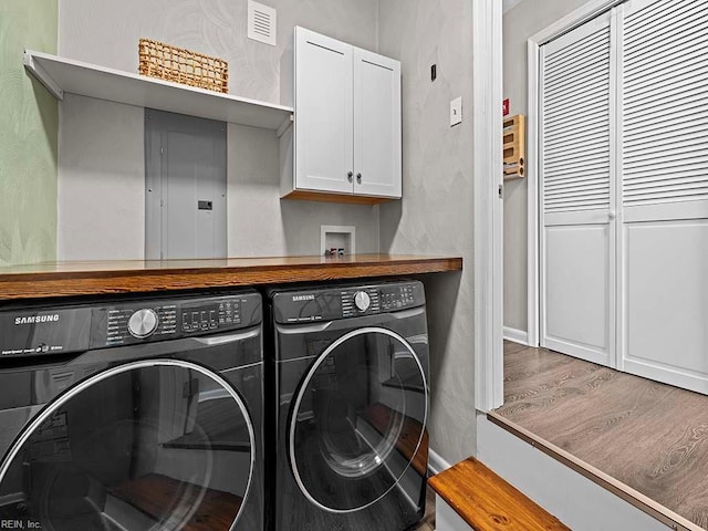 clothes washing area featuring separate washer and dryer, wood finished floors, visible vents, cabinet space, and electric panel