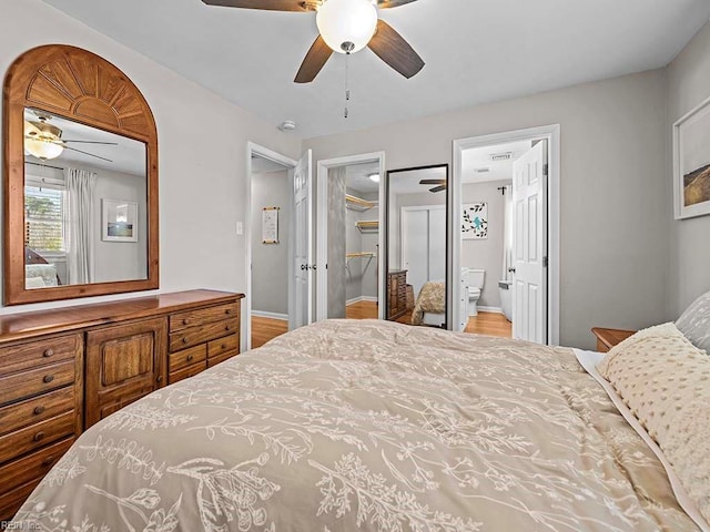 bedroom with ensuite bath, a ceiling fan, and baseboards