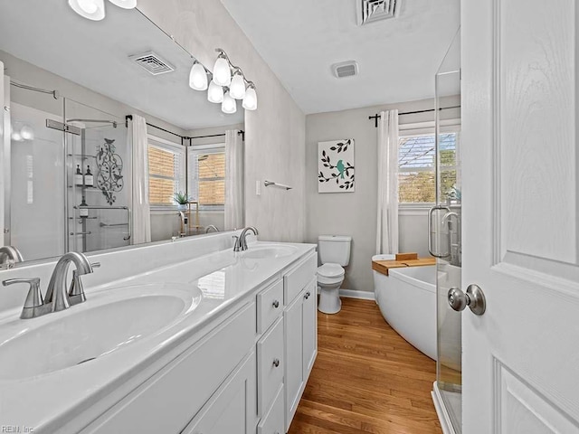 full bath featuring a stall shower, visible vents, a sink, and wood finished floors