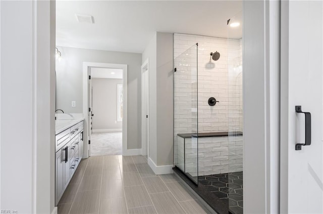 bathroom with a stall shower, vanity, and baseboards