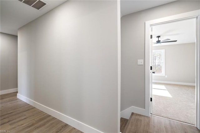 hallway with baseboards, visible vents, and light wood-style floors