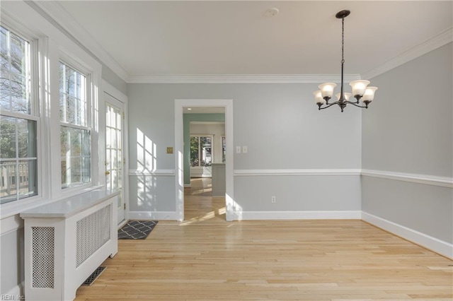 interior space with ornamental molding, radiator, light wood-style floors, an inviting chandelier, and baseboards