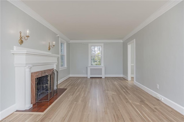 unfurnished living room featuring radiator heating unit, wood-type flooring, a fireplace, crown molding, and baseboards