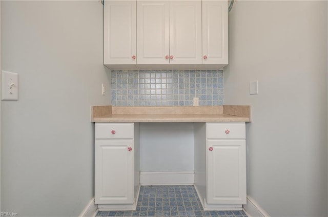 kitchen featuring decorative backsplash, white cabinetry, light countertops, and baseboards