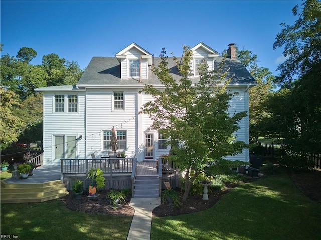 view of front of house with a chimney, a deck, and a front lawn