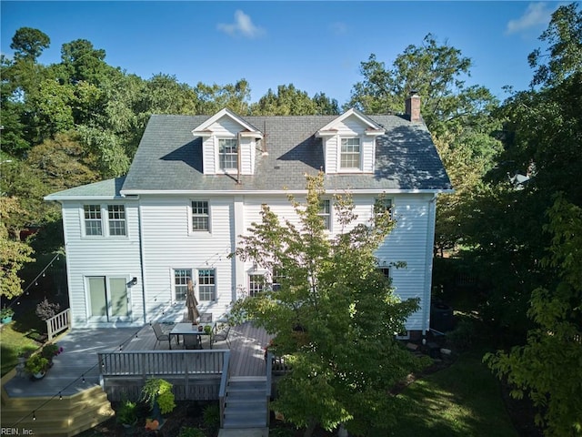 rear view of property featuring a deck, a shingled roof, and a chimney