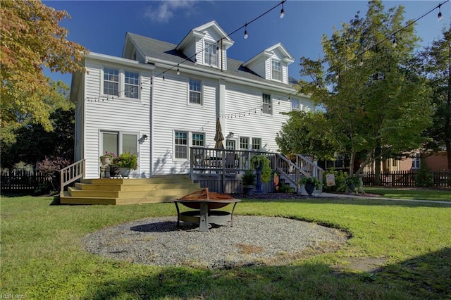 rear view of house featuring a fire pit, a deck, a lawn, and fence