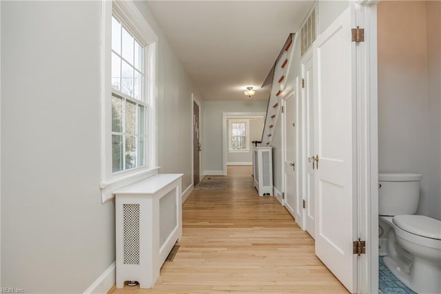 hallway featuring baseboards and light wood finished floors