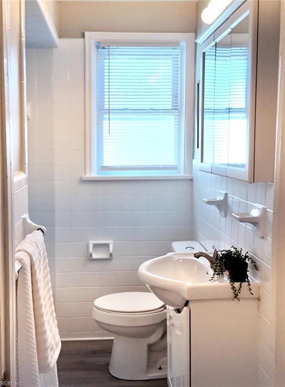 bathroom with toilet, wood finished floors, tile walls, and vanity