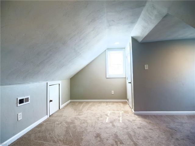 bonus room with carpet, vaulted ceiling, a textured ceiling, and baseboards