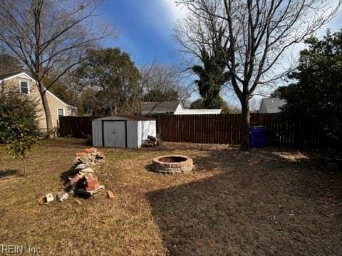 view of yard featuring a shed, fence, a fire pit, and an outbuilding