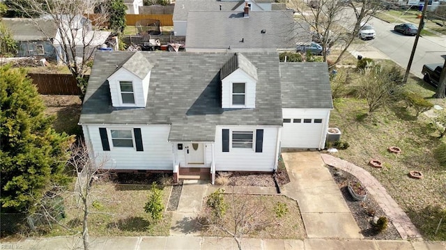 cape cod home featuring driveway, a shingled roof, and an attached garage