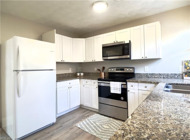 kitchen featuring light wood-type flooring, white cabinets, stainless steel appliances, and a sink