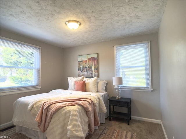 carpeted bedroom featuring a textured ceiling, multiple windows, and baseboards