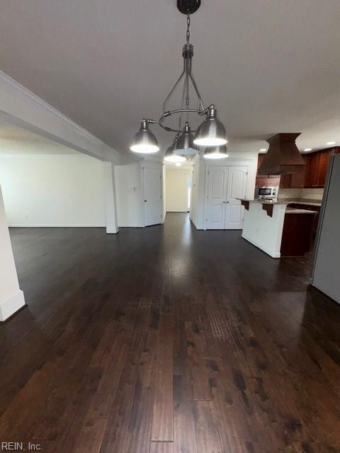 interior space featuring a breakfast bar area, dark wood-type flooring, open floor plan, light countertops, and custom range hood