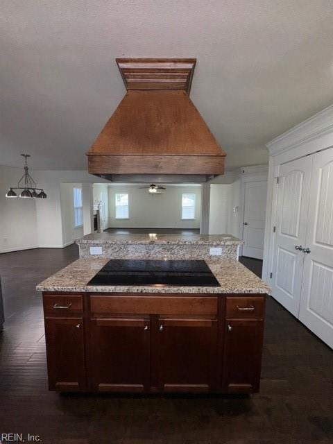 kitchen featuring light stone countertops, custom range hood, dark wood-style floors, and black electric cooktop