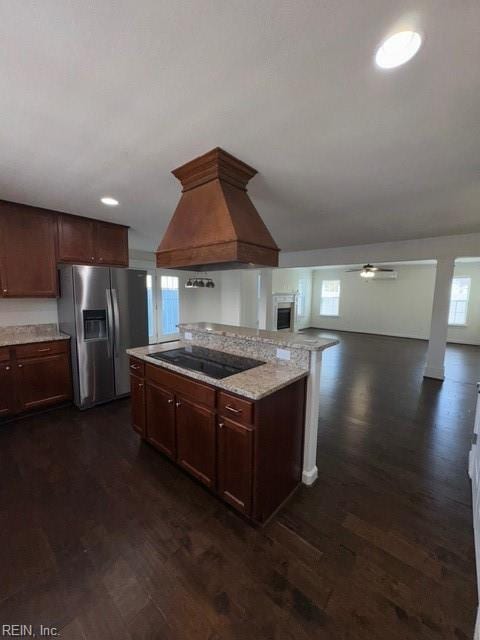 kitchen with a ceiling fan, stainless steel fridge with ice dispenser, dark wood-style floors, custom range hood, and black electric stovetop