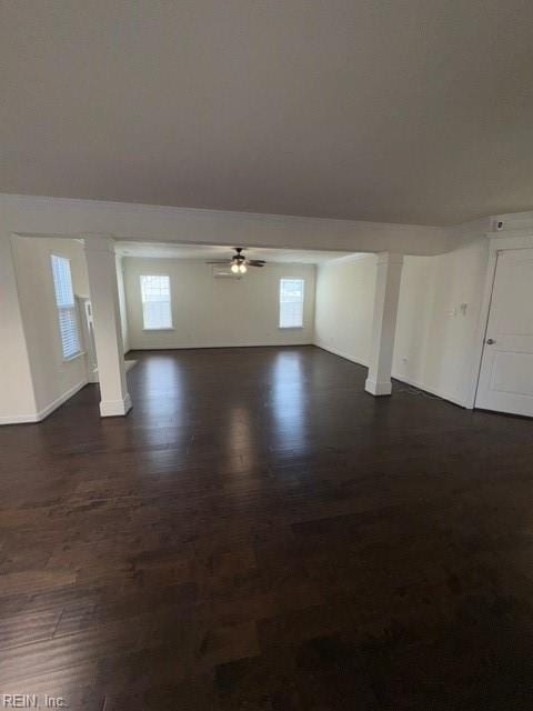 unfurnished living room featuring a healthy amount of sunlight, dark wood finished floors, and a ceiling fan