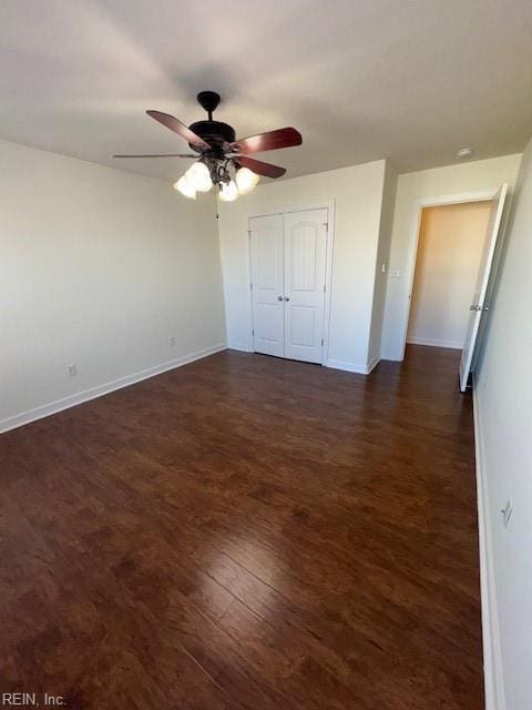 unfurnished bedroom with a closet, dark wood-style flooring, baseboards, and a ceiling fan