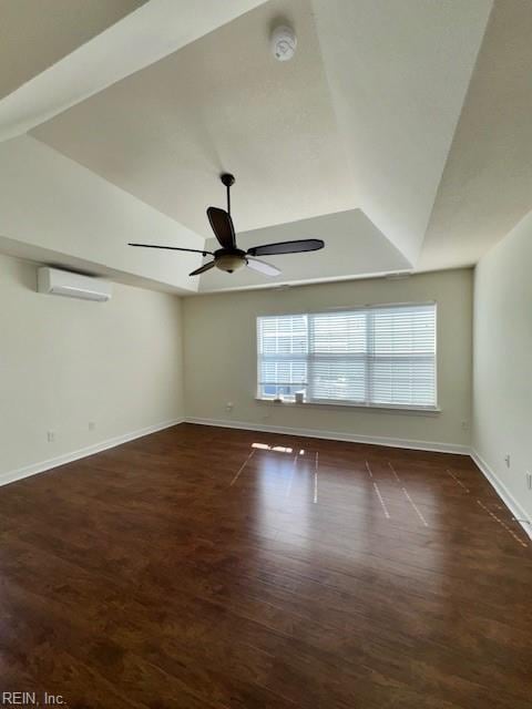 spare room with vaulted ceiling, an AC wall unit, ceiling fan, and wood finished floors