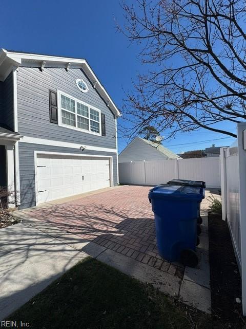 view of side of home featuring a garage, fence, and decorative driveway